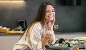 Femme qui mange dans sa cuisine