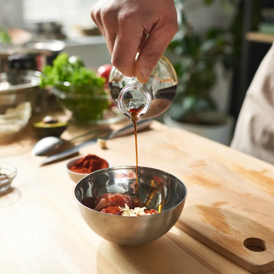 Cuisinier qui verse du vinaigre dans un saladier 