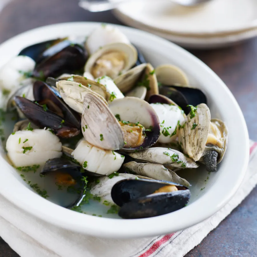 moules et coques cuites dans un bol soupoudrées d'herbes 