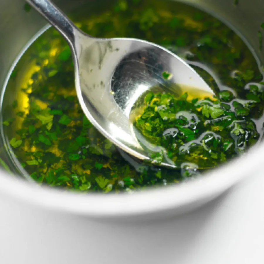 vinaigrette avec herbes aromatiques dans un bol avec une cuillère posée dans le récipient