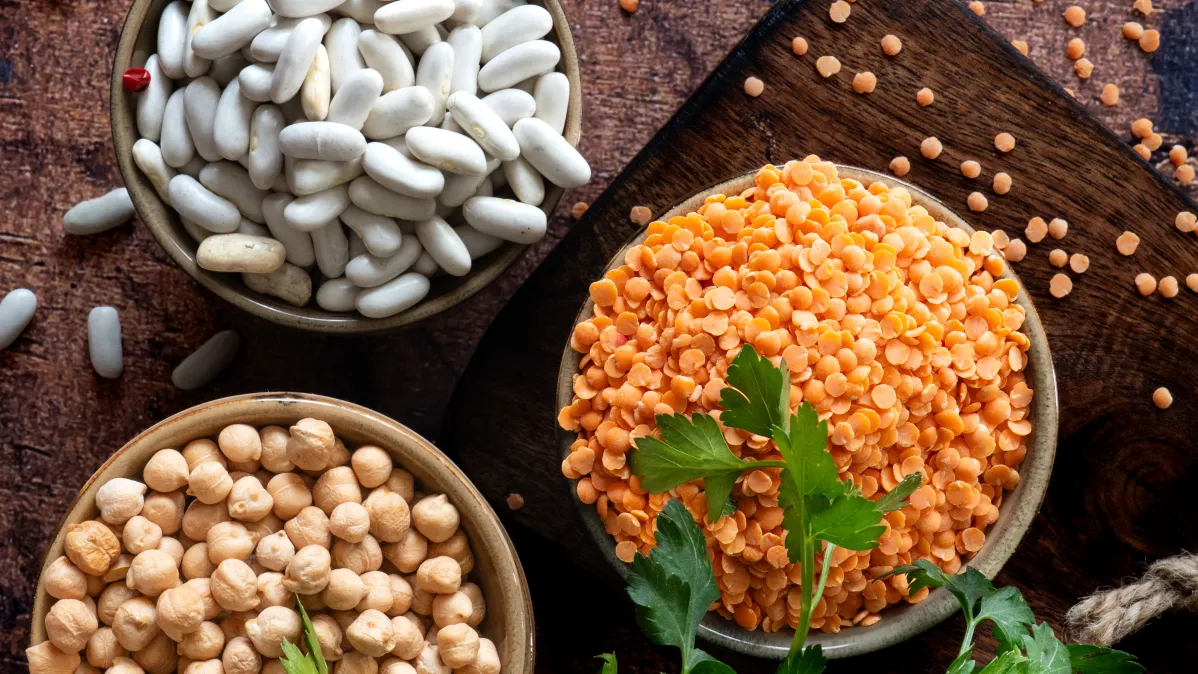 Trio de pois chiches, lentilles corail et haricots blancs sur fond bois