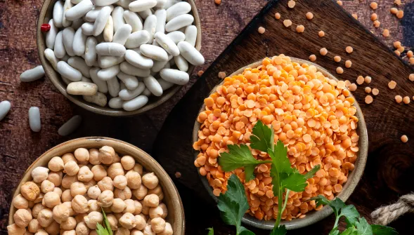 Trio de pois chiches, lentilles corail et haricots blancs sur fond bois