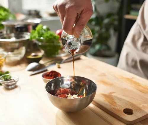 Cuisinier qui verse du vinaigre dans un saladier 