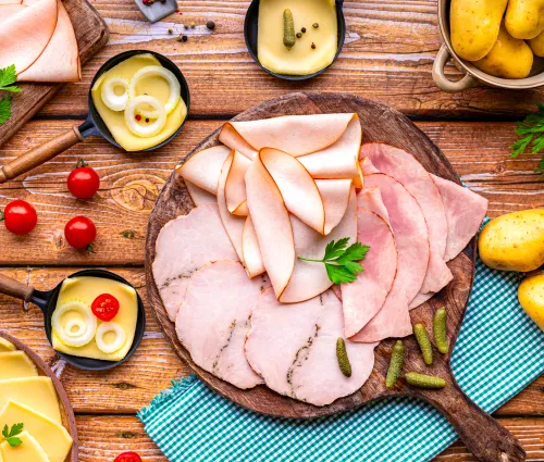 Table dressée pour une raclette, fromage, charcuterie tomate 