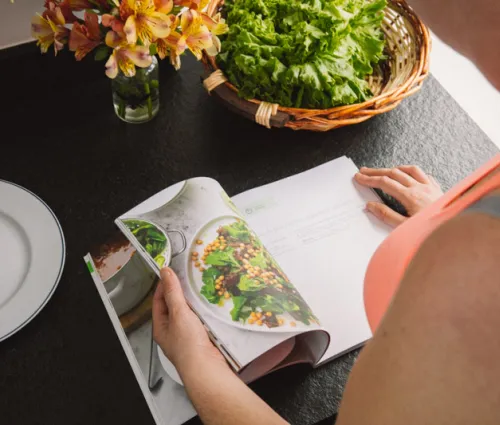 femme de dos qui lit un livre de cuisine