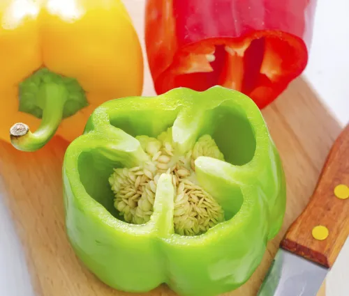 poivron jaune, rouge et vert sur une planche à découper avec un couteau 