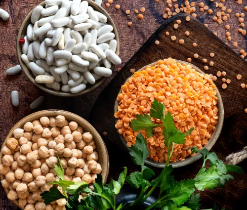 Trio de pois chiches, lentilles corail et haricots blancs sur fond bois